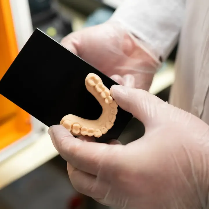 Zahnmodell wird vor dem 3D-Drucker begutachtet