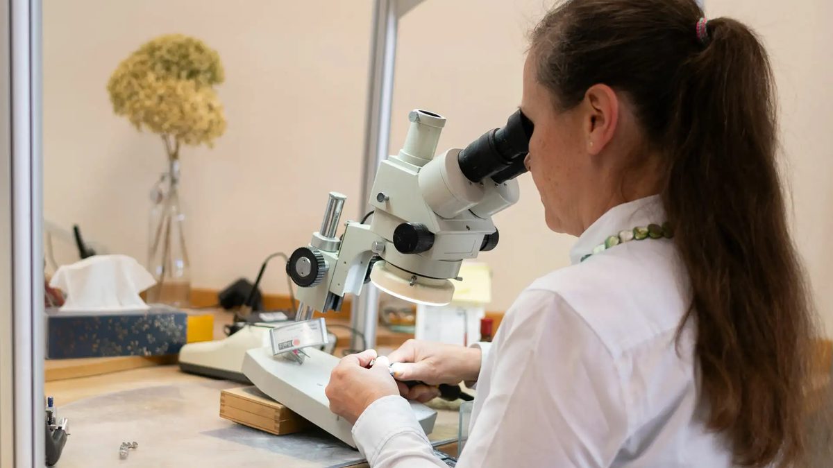 Zahntechnikerin arbeitet am Mikroskop