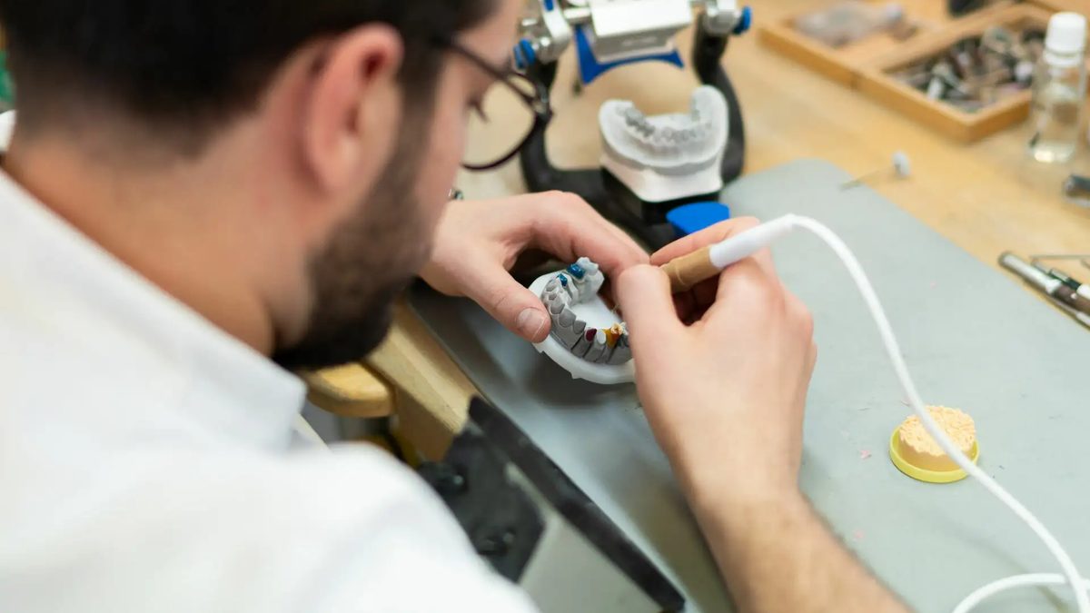 Zahntechniker arbeitet am Laborplatz an einem Modell im Artikulator